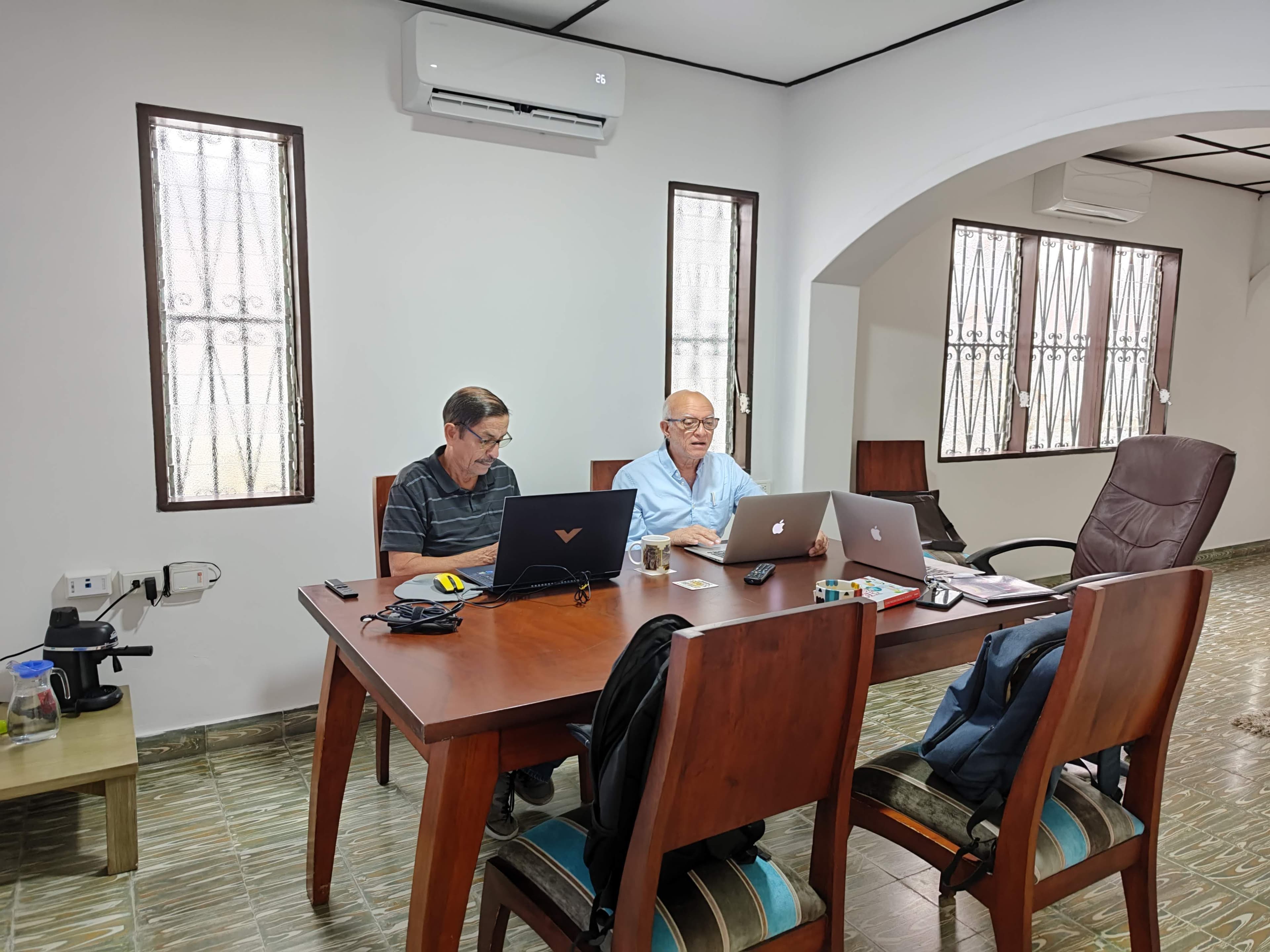 Dos personas trabajando con laptops en la mesa principal