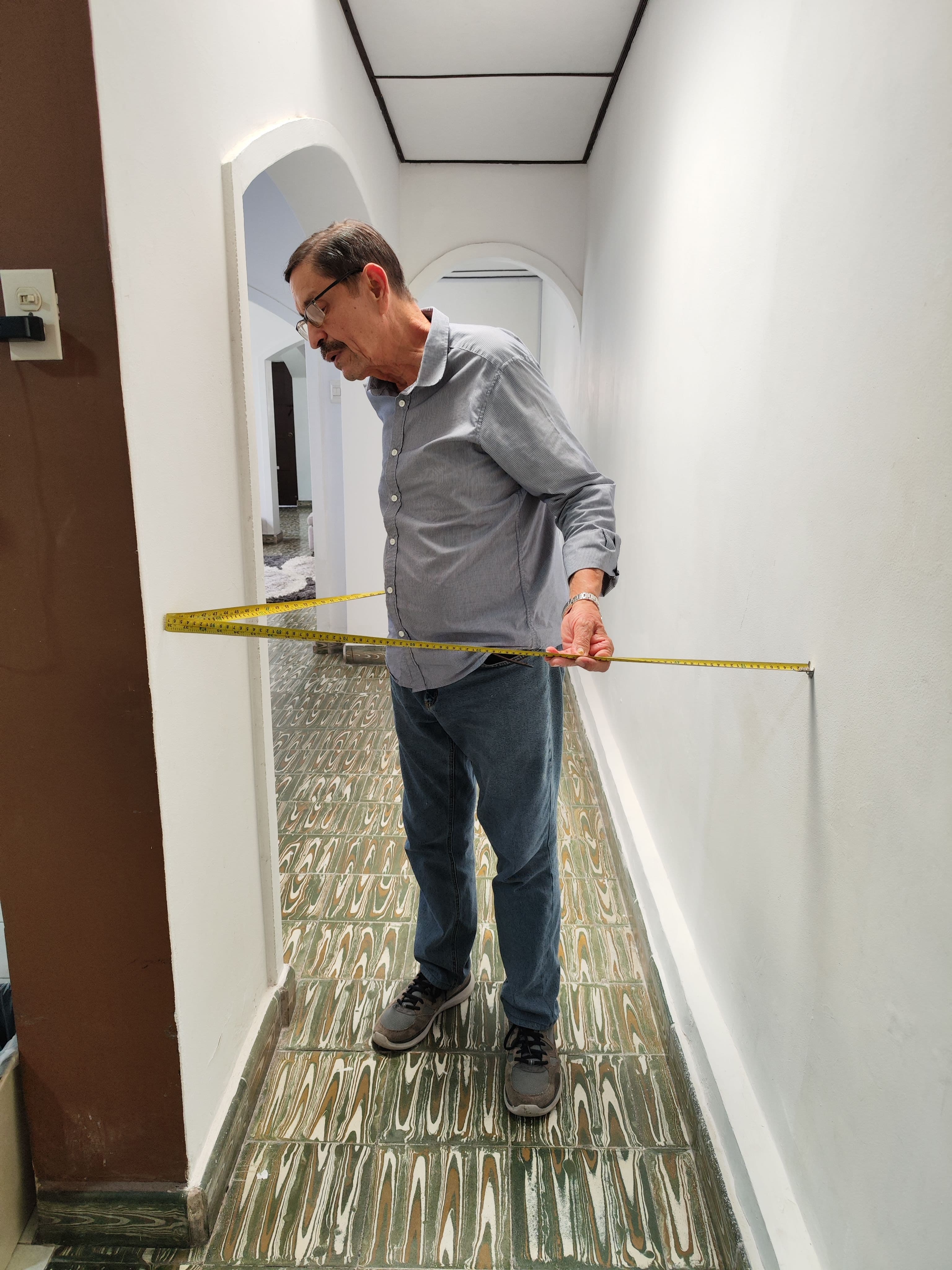 Persona tomando medidas con cinta métrica en pasillo